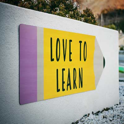 Ein an eine Mauer montiertes Schild in Form eines Bleistifts mit der Aufschrift "LOVE TO LEARN".