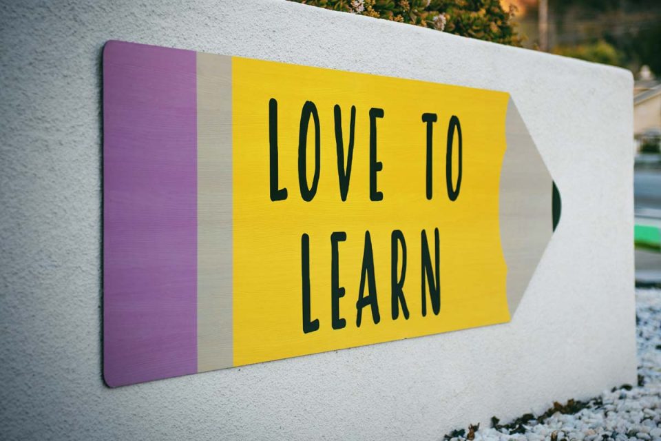 Auf eine Wand gemalt ist ein Graffiti-Buntstift, auf dem steht: LOVE TO LEARN.