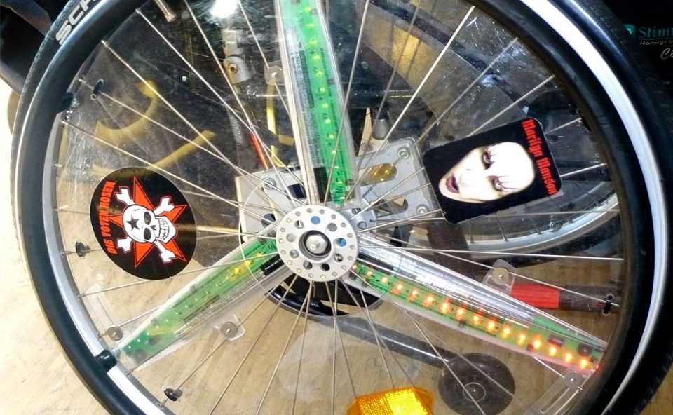 Rad eines Rollstuhls, beklebt mit Stickern der Band Die Toten Hosen und des Musikers Marilyn Manson.