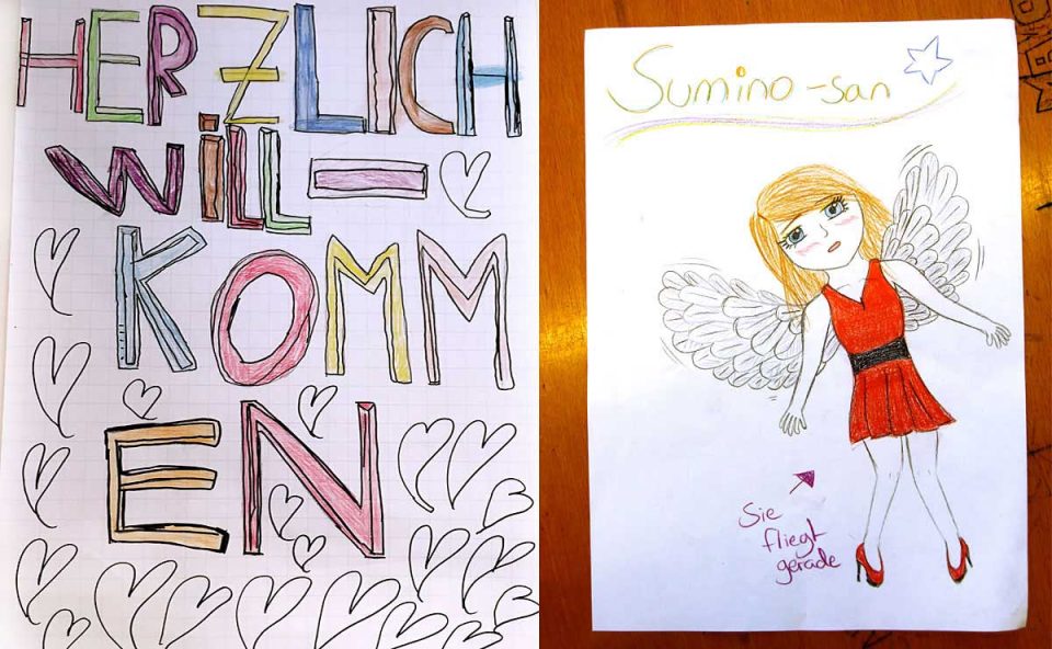 Selbstgemalte Plakate: Auf dem linken steht "Herzlich willkommen", das rechte zeigt eine fliegende Manga-Comicfigur, die Schülerin Sumino.